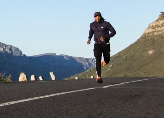 A man is running on the road with mountains in the background