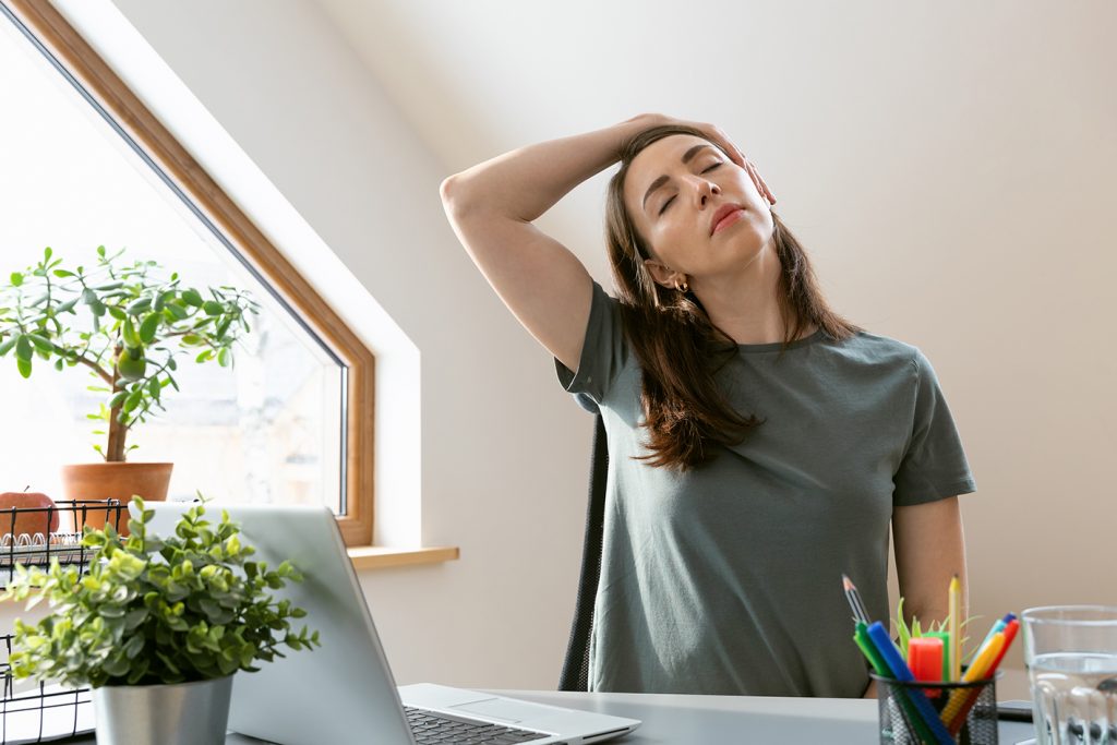 Woman exercising at home office by stretching her neck