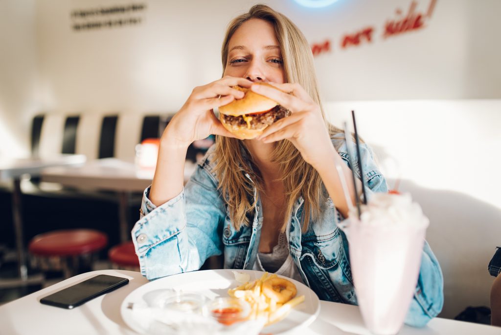 A young woman is eating a hamburger in a restaurant