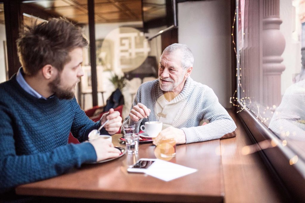 Two men sitting at a table and having coffee in a public caffee
